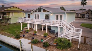 A two-story house with a covered patio, outdoor furniture, and a small pool. - Waterfront | Communal Pool | Dock | Pet-Friendly! (Rockport)