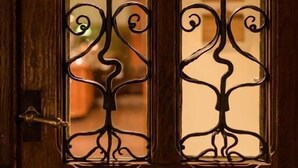 Una puerta de madera con un diseño metálico decorativo que presenta motivos florales y de vides.