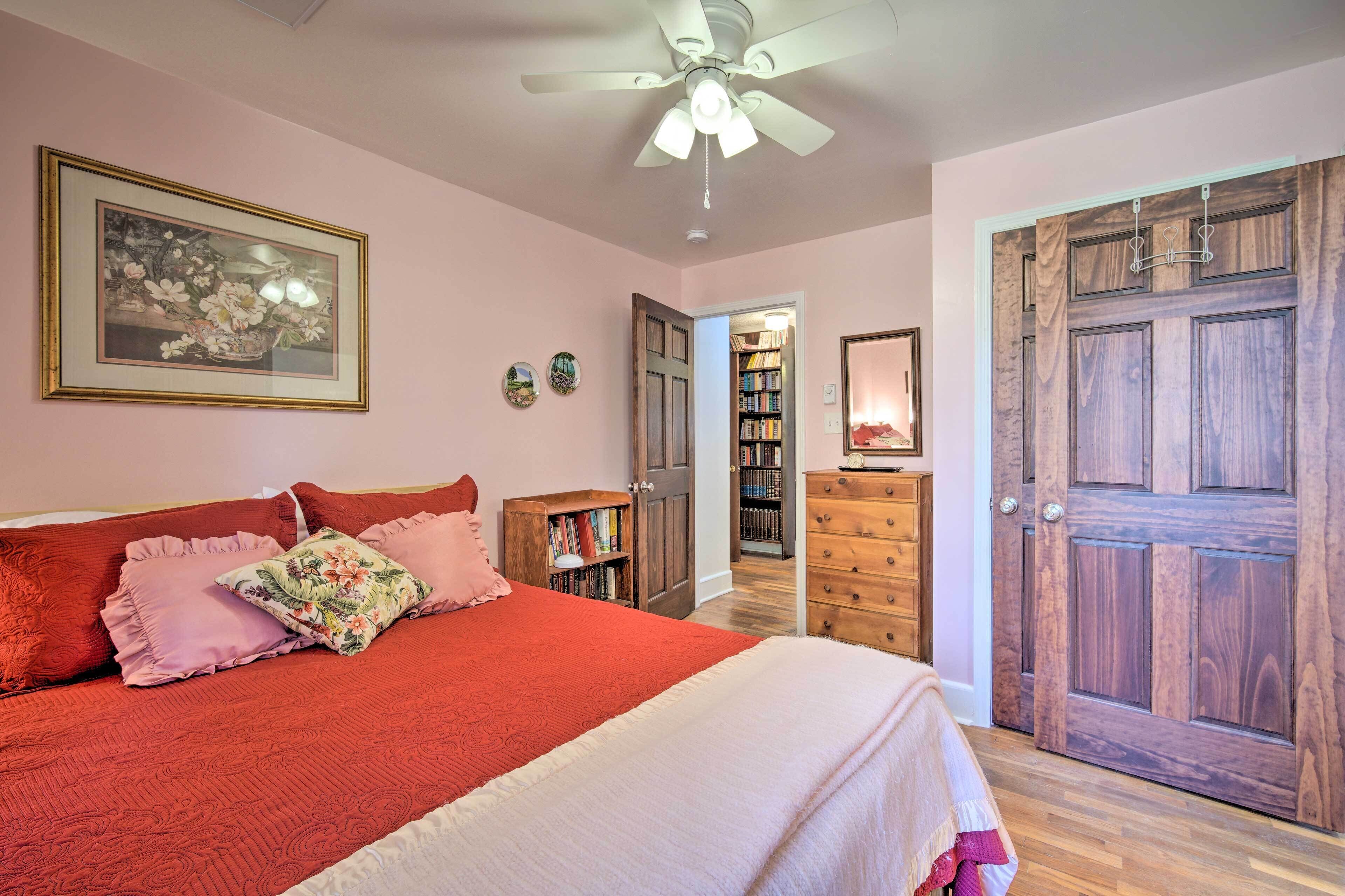 A bedroom with a bed, a ceiling fan, a bookshelf, and a wooden door.