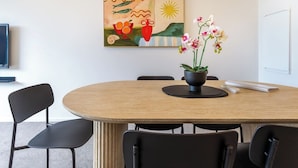 A conference room with a round table, black chairs, a painting on the wall, and a potted orchid on the table. - City Stay, Sleeps 6 - Walk to One NZ Stadium (Christchurch)