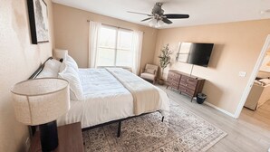 A bedroom with a bed, a chair, a TV, and a ceiling fan. - Beautiful Historic Lebanon Illinois 2 Bedroom Villa (Lebanon)