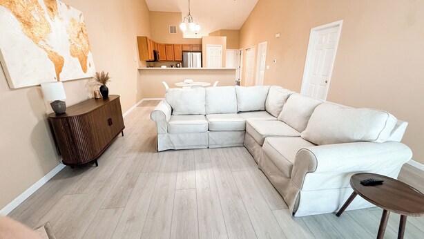 A living room with a sectional sofa, a wooden cabinet, and a small table. - Beautiful Historic Lebanon Illinois 2 Bedroom Villa (Lebanon)