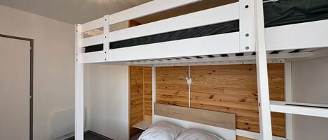 A bunk bed room with a wooden headboard, a white bed, and a ceiling light fixture.
