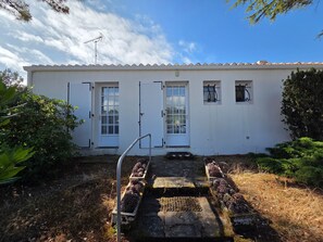 A white building with a tiled roof, a metal antenna, and a set of steps leading to a door. - Family house 6 pers, pets allowed, near beach (La Faute-sur-Mer)