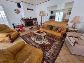 A living room with leather sofas, a fireplace, a television, and a patterned rug. - Family house 6 pers, pets allowed, near beach (La Faute-sur-Mer)