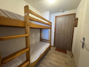 A bunk bed room with a wooden door and a small mat at the entrance. - Charming apartment near slopes with parking (Thollon-les-Mémises)