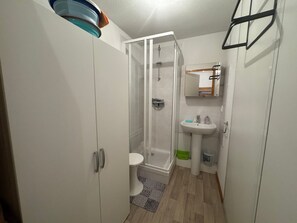 Ein kleines Badezimmer mit Dusche, Toilette und Waschbecken.