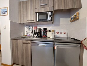 A compact kitchen with a microwave, coffee maker, and dishwasher. - Charming apartment near slopes with parking (Thollon-les-Mémises)