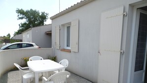 A patio area with a white table and chairs, a small window, and a door. - Single-storey cottage near beach with parking in L'Aiguillon-sur-Mer (L'Aiguillon-sur-Mer)