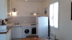 A compact kitchen with a washing machine, microwave, and a small dining table. - Single-storey cottage near beach with parking in L'Aiguillon-sur-Mer (L'Aiguillon-sur-Mer)