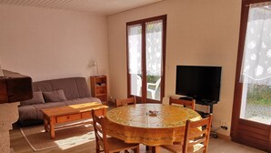 Una sala de estar acogedora con una mesa redonda de madera, un sofá y un televisor.
