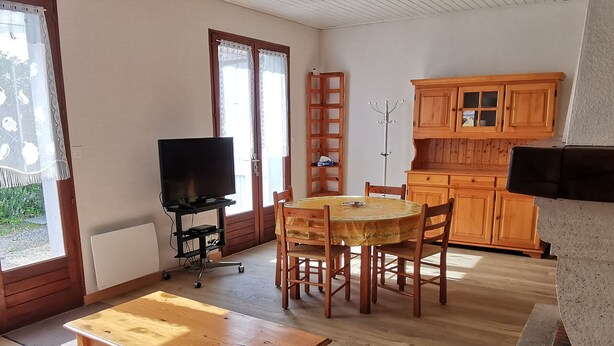 Una sala de estar acogedora con una mesa de madera, un sofá y un televisor sobre un mueble.