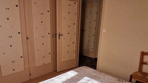 Un dormitorio con cama, suelo de madera y un armario con varios compartimentos.