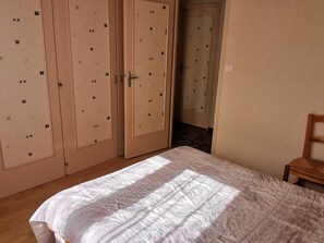 Ein Schlafzimmer mit einem Bett, Holzboden und einem Schrank mit mehreren Fächern.