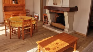 Un comedor con una mesa y sillas de madera, un armario de madera y una chimenea.