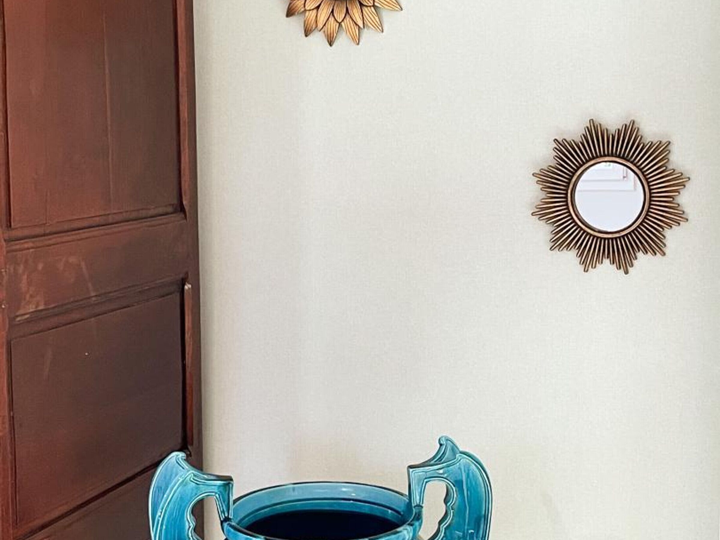 Ein Zimmer mit Holztür, einem blauen Keramiktopf und zwei Wandbildern.