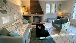 Ein Wohnzimmer mit Kamin, zwei Sofas, einem Couchtisch und einem großen Fenster.