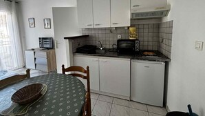 Een compacte keuken met witte kastjes, een magnetron, een broodrooster en een koffiezetapparaat.