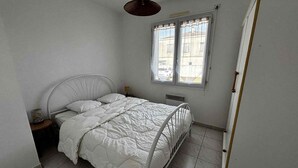Een slaapkamer met een bed, een raam, een radiator en een kledingkast.