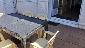 Eine Terrassenfläche mit Tisch und Stühlen, einer Schiebetür und einer Treppe, die zu einer oberen Etage führt.