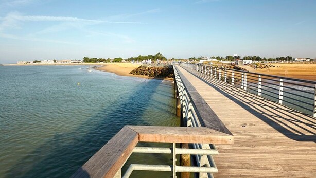 A wooden pier extending into calm waters with a sandy beach and distant buildings in the background. - Quiet house near beach with parking and pets allowed (La Tranche-sur-Mer)