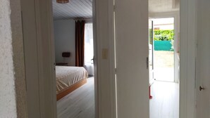 A hallway leading to a bedroom with a bed and a chair. - Quiet house near beach with parking and pets allowed (La Tranche-sur-Mer)