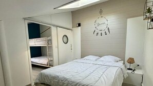 A bedroom with a bunk bed, a single bed, a wall clock, a dream-themed decoration, and a bedside lamp. - Cozy house for 4, near center and beach, with parking (La Tranche-sur-Mer)