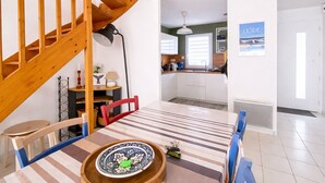 Ein Essbereich mit einer Holztreppe, einer Küche im Hintergrund und einem Poster an der Wand.