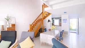 Ein modernes Wohnzimmer mit Treppe, Essbereich und einer Küche im Hintergrund.