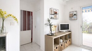 Ein modernes Wohnzimmer mit Fernseher, dekorativen Regalen und einer Tür zu einem weiteren Raum.