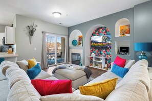 Una sala de estar con un sofá, una chimenea, un televisor y una estantería.