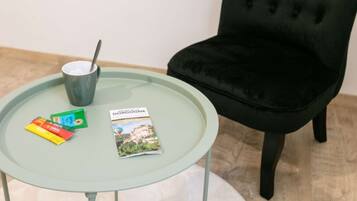 Una mesa redonda de vidrio con una silla de terciopelo negro, una taza y folletos de viajes.