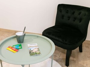 Un tavolo rotondo in vetro con una poltrona in velluto nero, una tazza e diverse brochure di viaggio.