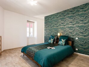 A bedroom with a bed, a window, and a patterned wall.