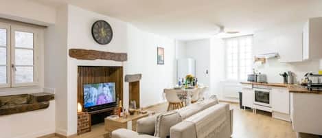 Un salon comprenant un téléviseur, une cheminée, un canapé et un coin repas avec une table et des chaises.