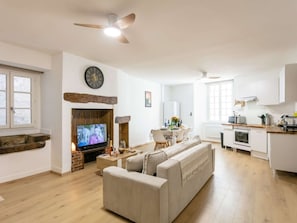 A living room with a television, a fireplace, a sofa, and a dining area with a table and chairs. - Charming apartment, 4 people, medieval village Martel, Pets allowed, Free WiFi (Martel)