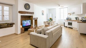 A modern living room with a fireplace, a television, a sofa, and a dining area with a table and chairs.
