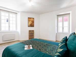 Una camera da letto con un letto, una finestra, un termosifone e una mensola a parete.