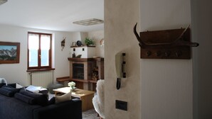Una sala de estar con chimenea, un sofá, una mesa de centro y un estante de madera con un teléfono.