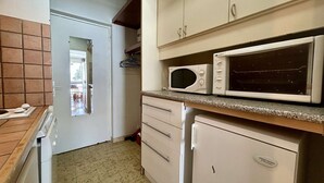 A compact kitchen with a microwave, a small refrigerator, and a door leading to a dining area. - Studio for 4 near slopes with free wifi and parking (Le Dévoluy)