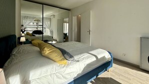 Une chambre à coucher moderne avec un grand lit, un miroir et une armoire.