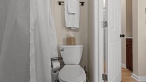 A bathroom with a toilet, a towel rack, and a shower curtain.