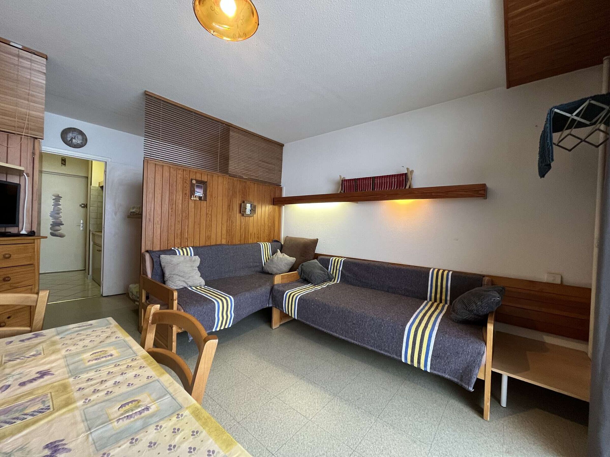 A cozy room with a sofa set, wooden panel wall, and a small table with a patterned tablecloth.