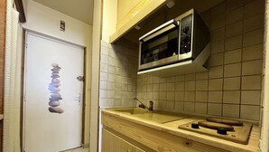 Une cuisine équipée d’un four à micro-ondes, de meubles en bois et d’un pare-feu en carreaux.