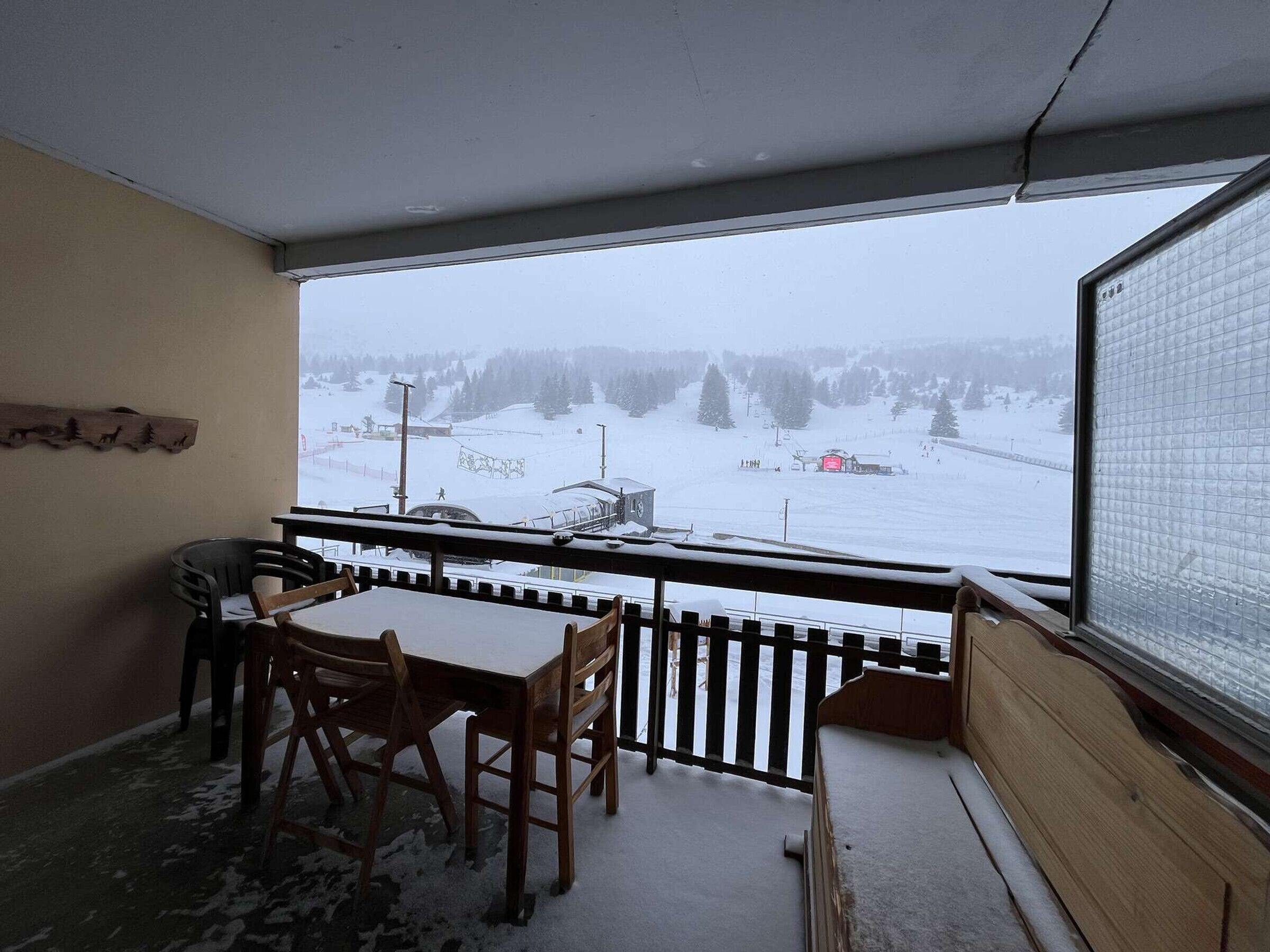 A room with a view of a snowy landscape, a wooden table, and chairs.