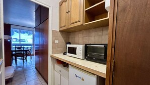 Eine kleine Küche mit Mikrowelle, Toaster und Kühlschrank.