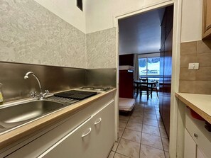 A modern kitchen with a stainless steel sink, wooden countertop, and a view of a dining area through an open doorway. - Studio for 4 in SuperDévoluy with WIFI (Le Dévoluy)