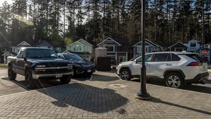 A parking area with several cars, a stop sign, and houses in the background. - Cozy Corner on Trumpeter (Colwood)