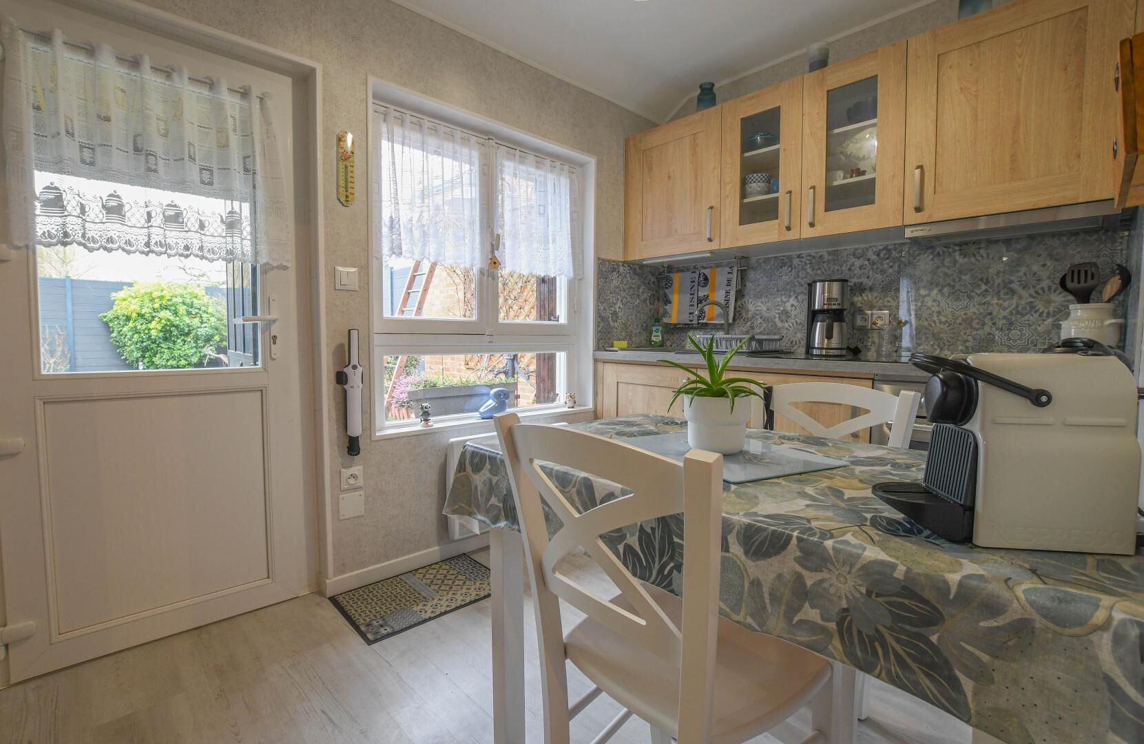 A kitchen with wooden cabinets, a coffee machine, and a dining table with chairs.
