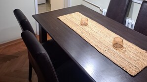 A dining area with a dark wooden table, two chairs, a woven placemat, and a pendant light fixture. - Cozy apartment in lovely and peaceful part of Belgrade (Belgrade)